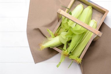 Beyaz ahşap arka plan üzerinde taze mısır koçanları ile Sepet