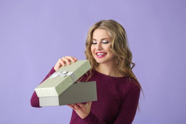 Renkli arka planda hediye kutusu olan güzel genç bir kadın.