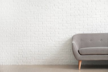 Beyaz tuğla duvara yakın modern kanepe
