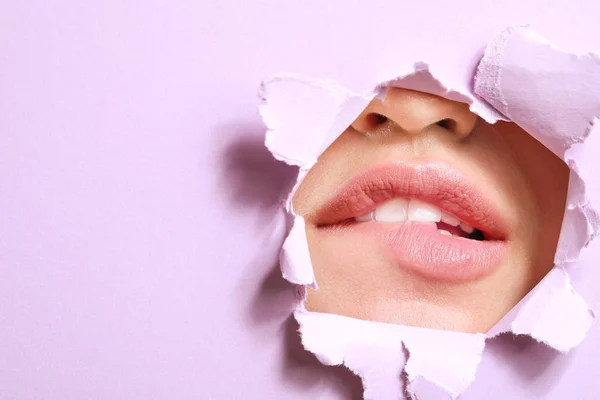 Labios de hermosa mujer joven visible a través del agujero en papel de color — Foto de Stock