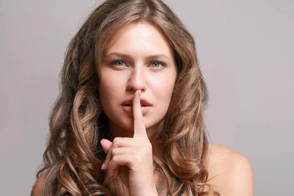 Beautiful young woman showing silence gesture on grey background — Stock Photo, Image