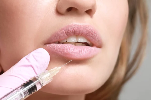 Jeune femme recevant une injection de charge dans les lèvres, gros plan — Photo
