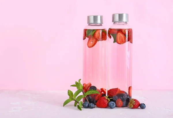 Flaskor av välsmakande infunderas vatten på färg bakgrund — Stockfoto
