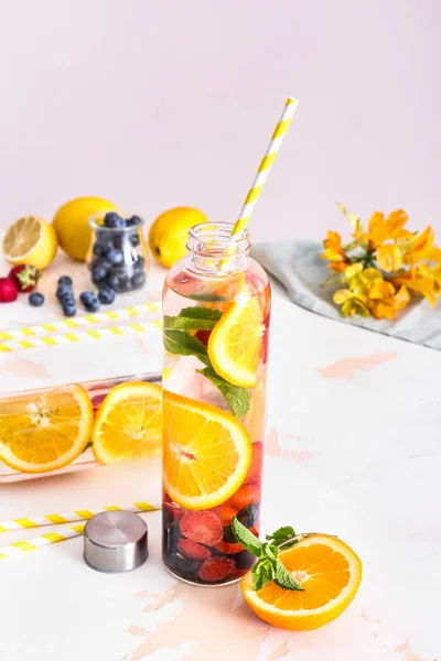 Bottle of tasty infused water on light table — Stock Photo, Image