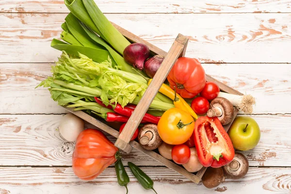 Basket with assortment of fresh vegetables on white wooden background — Stock Photo, Image