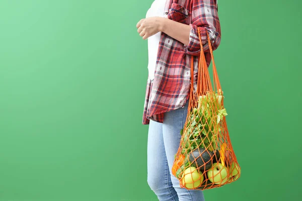 Bolso ecológico de malla con productos sobre fondo de color para mujer —  Fotos de Stock