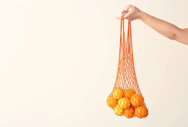 Bolso ecológico de malla de mano femenina con frutas sobre fondo claro —  Fotos de Stock