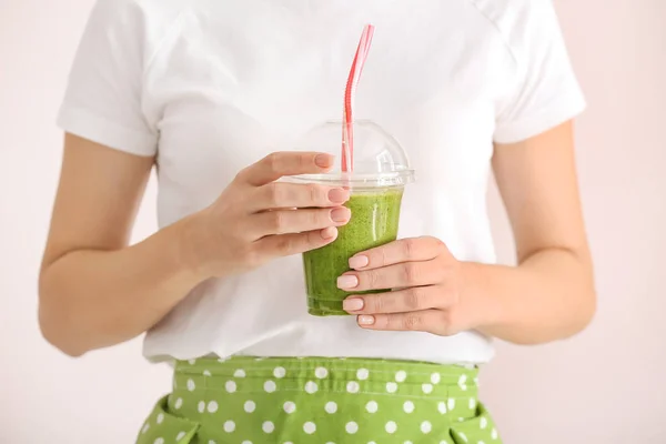 Young woman with tasty smoothie in cup on light background, closeup — Stock Photo, Image