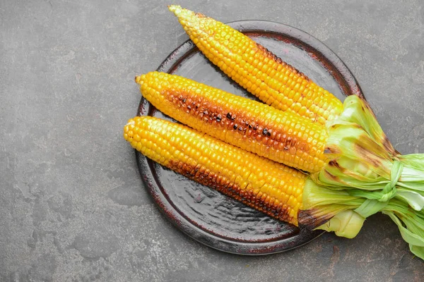 Plate with tasty grilled corn cobs on grunge background — Stock Photo, Image