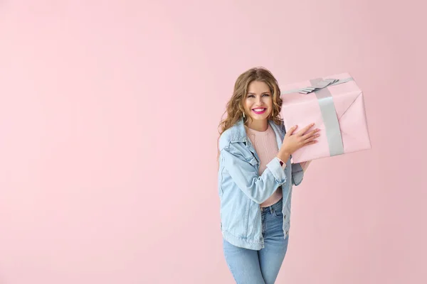 Happy young woman with gift box on color background — Stock Photo, Image