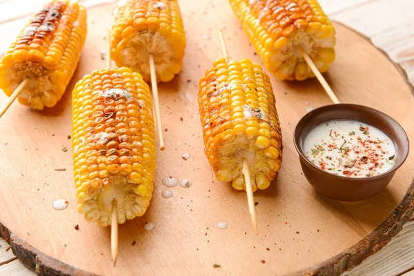Tasty grilled corn cobs on wooden stand — Stock Photo, Image