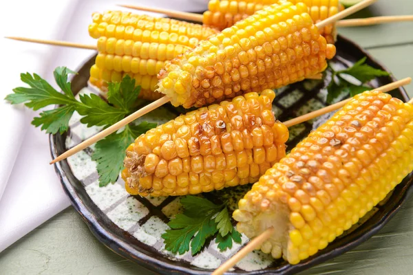 Placa con sabrosas mazorcas de maíz a la parrilla en la mesa —  Fotos de Stock