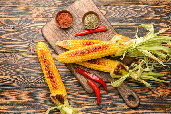 Composition with tasty grilled corn cobs on wooden background