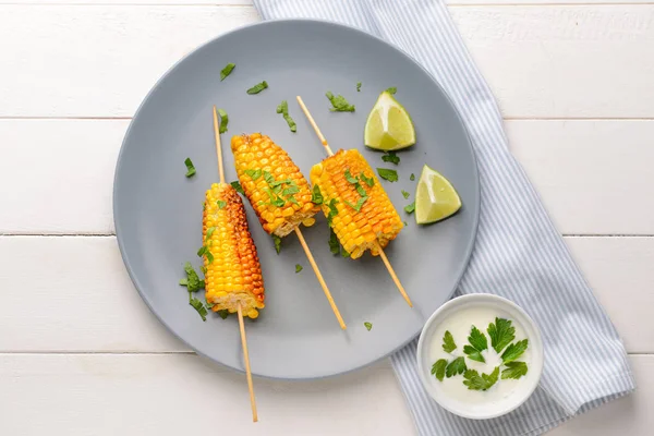 Plate with tasty grilled corn cobs on white wooden background — Stock Photo, Image