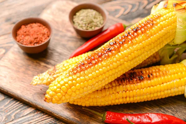 Sabrosas mazorcas de maíz a la parrilla sobre fondo de madera —  Fotos de Stock