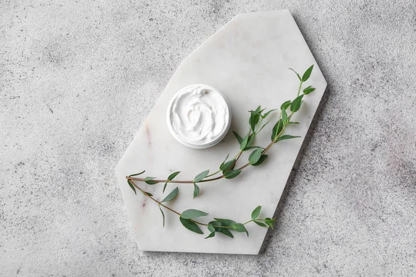 Board with body cream and eucalyptus on grey background — Stock Photo, Image
