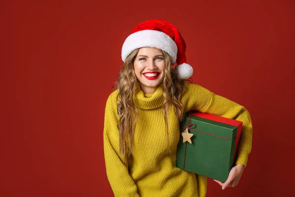 Beautiful young woman with Christmas gift on color background — Stock Photo, Image