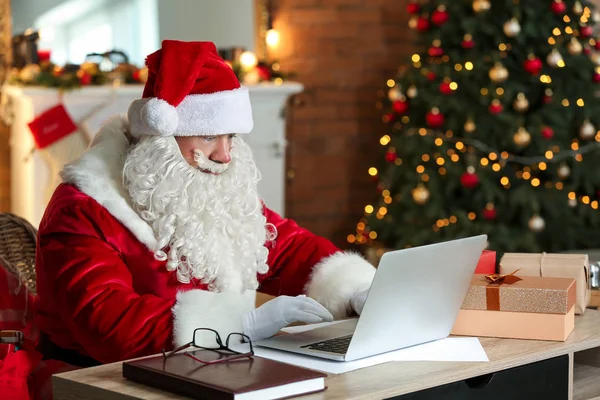 Jultomten med laptop i rummet dekorerad för julen — Stockfoto