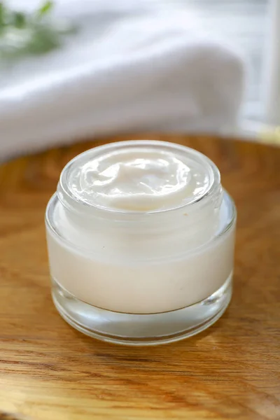 Jar of natural cream on wooden plate