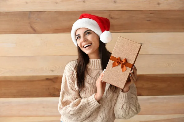 Schöne junge Frau mit Weihnachtsgeschenk auf Holzgrund — Stockfoto