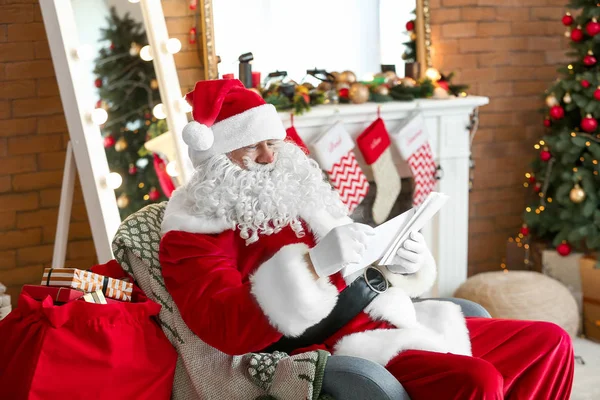 Santa Claus reading wish list in room decorated for Christmas — Stock Photo, Image