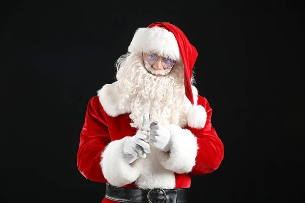 Święty Mikołaj z pieniędzmi na ciemnym tle — Zdjęcie stockowe