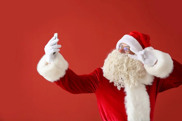 Portrait of Santa Claus taking selfie on color background — Stock Photo, Image