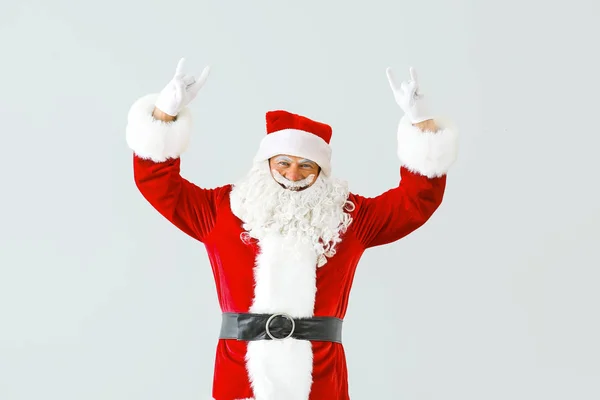 Retrato de Papai Noel legal mostrando "chifres do diabo" gesto no fundo de luz — Fotografia de Stock