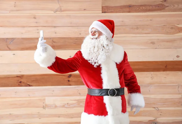 Retrato de Papai Noel tirando selfie em fundo de madeira — Fotografia de Stock