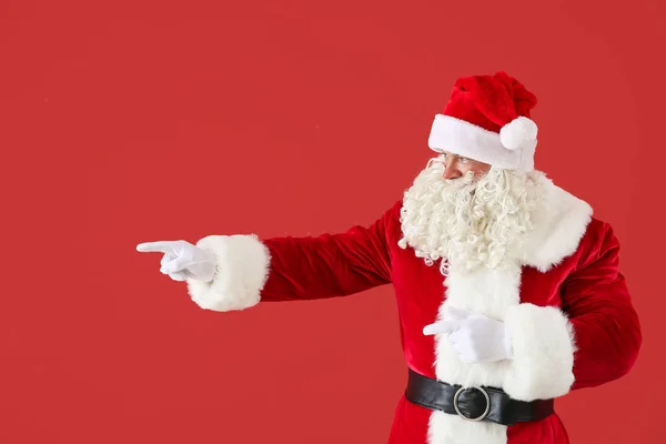 Portrait of Santa Claus pointing at something on color background — Stock Photo, Image