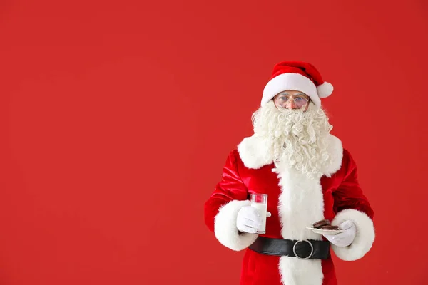 Santa Claus s mlékem a sušenkama na barevném pozadí — Stock fotografie