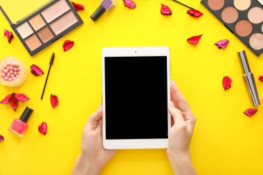 Renkli arka planda tablet bilgisayar ve kozmetik ile Kadın eller