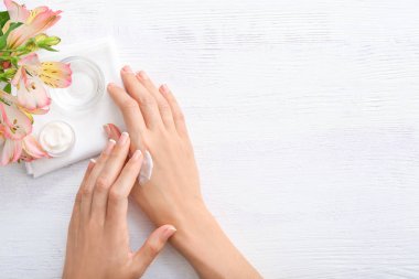 Beyaz ahşap arka plan üzerinde doğal krem ile Kadın eller