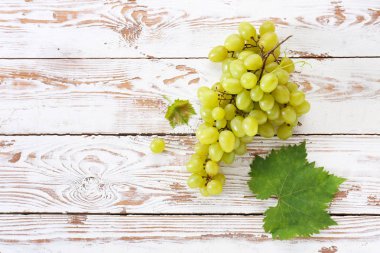 Tasty fresh grapes on white wooden background clipart