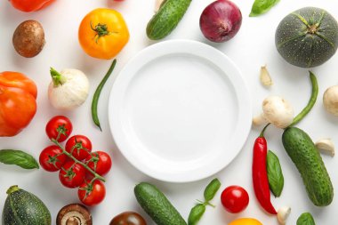 Beyaz arka planda farklı taze sebzeler ve tabak
