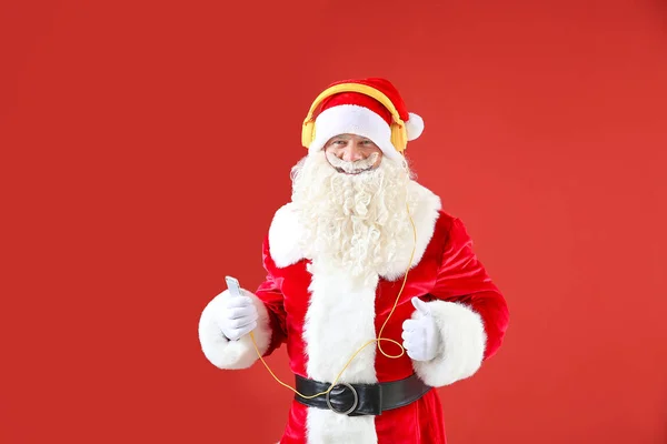 Portrait of cool Santa Claus listening to music on color background — Stock Photo, Image