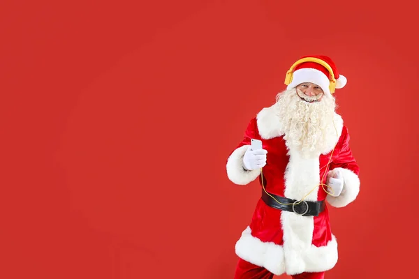Porträt eines coolen Weihnachtsmannes, der Musik auf farbigem Hintergrund hört — Stockfoto