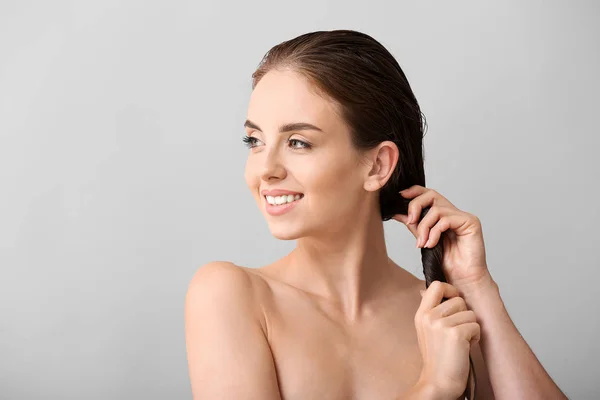 Mulher bonita depois de lavar o cabelo contra fundo cinza — Fotografia de Stock