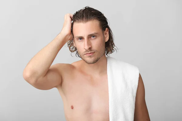 Przystojny młody człowiek po umyciu włosów na szarym tle — Zdjęcie stockowe
