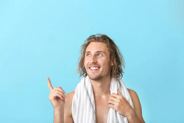 Handsome young man after washing hair pointing at something against color background — Stock Photo, Image