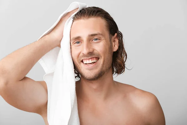 Knappe man vegen haren na het wassen tegen grijze achtergrond — Stockfoto