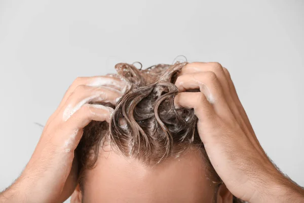 Schöner junger Mann, Haare waschen vor grauem Hintergrund, Nahaufnahme — Stockfoto