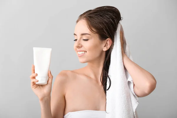 Hermosa mujer joven limpiando el cabello después de lavar contra el fondo gris —  Fotos de Stock