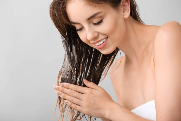 Mulher bonita lavando o cabelo contra fundo cinza — Fotografia de Stock