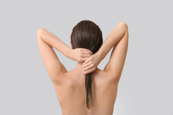 Piękna młoda kobieta po umyciu włosów na szarym tle, widok z tyłu — Zdjęcie stockowe