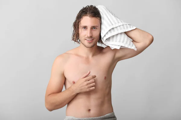 Красивий чоловік витирає волосся після миття на сірому фоні — стокове фото