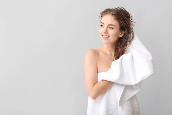 Krásná mladá žena, která si otírala vlasy po praní na šedé pozadí — Stock fotografie