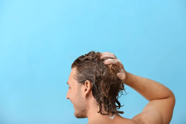 Όμορφος νέος άνθρωπος πλύσιμο των μαλλιών με φόντο χρώμα — Φωτογραφία Αρχείου
