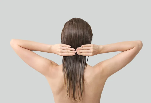 Красивая молодая женщина после мытья волос на сером фоне, вид сзади — стоковое фото