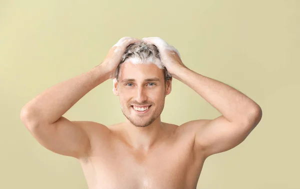 Jóképű fiatalember mosás haj ellen színes háttér — Stock Fotó